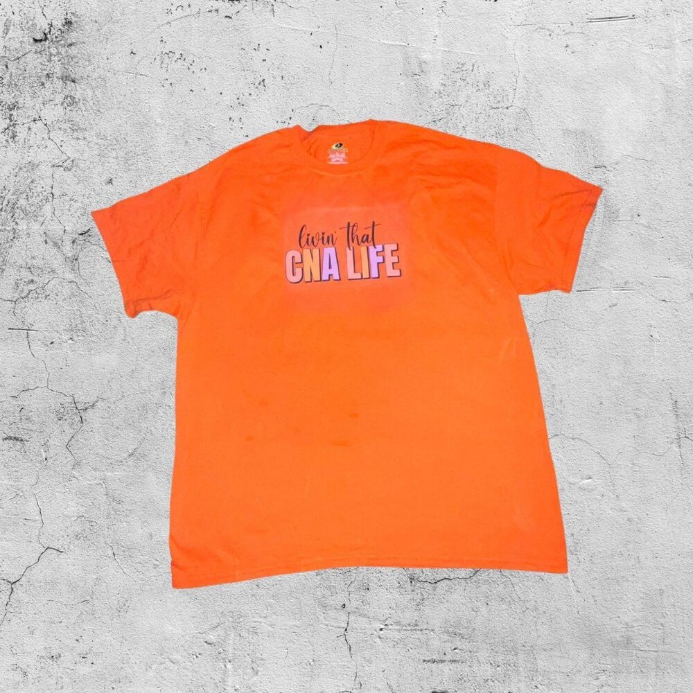 Bright orange “Livin’ That CNA Life” graphic tee.